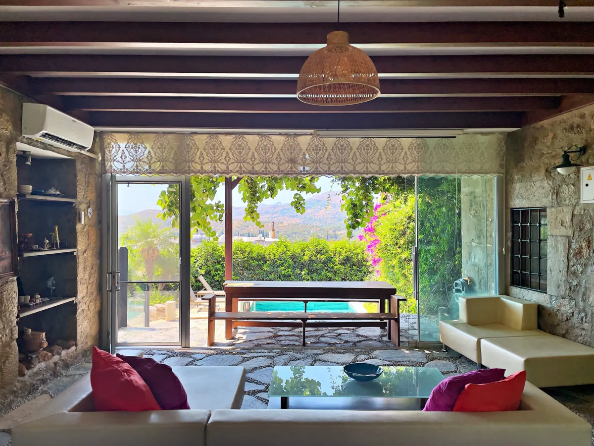 Villa Celestia'nın Bodrum'da bahçeye açılan taş duvarlı salonu