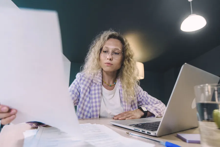 A property owner working through paperwork at a laptop